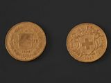 two gold coins on a black surface with a black background