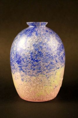 un vase bleu et jaune posé sur une surface noire