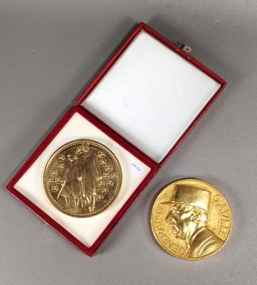 une image représentant une médaille d'or dans un coffret rouge, à côté d'une pièce d'or
