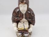 a figurine of a man holding a book on a white surface