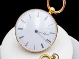 a gold clock and a key on a white plate