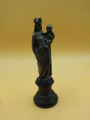 une statue noire représentant une femme tenant un enfant dans ses bras, posée sur une table