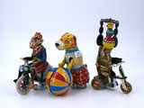 three figurines of dogs riding on tricycles