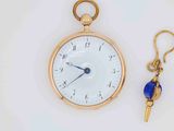 a gold pocket watch with a blue bead key hanging from it