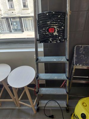 two stools and a ladder in the corner of a room