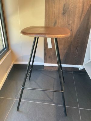un tabouret avec une assise en bois, placé devant une fenêtre