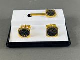 a pair of black and gold cufflinks with a white box