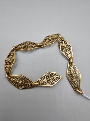 gros plan d'un bracelet en or sur une surface blanche