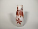 a white vase with brown leaves on it on a table
