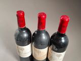 three bottles of red wine are lined up on a table