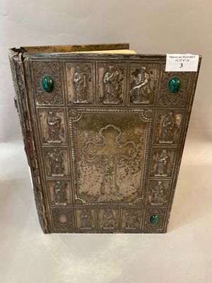 an old silver book with green buttons on it sitting on a white surface