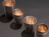 four silver cups are lined up in a row on a black surface