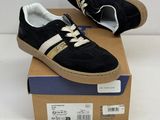 black and gold sneakers with white laces on top of a cardboard box