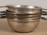 three metal bowls sitting on a table with spoons in them