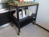 a black cart with a wooden top in a kitchen
