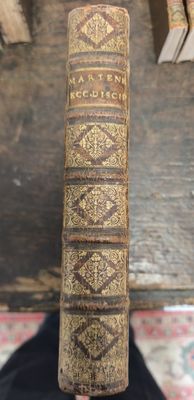 un vieux livre posé sur une table à côté d'une pile de livres