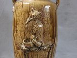 a brown vase with a bird on it sitting on a branch