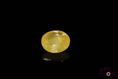 a yellow sapphire stone on a black surface