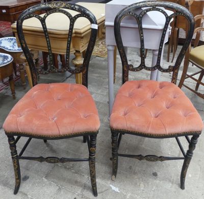 une paire de chaises peintes en noir avec des coussins d'assise rembourrés orange