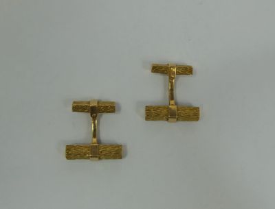 two pairs of gold cufflinks on a white surface