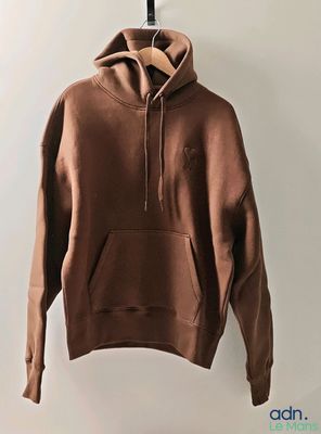 a brown hoodie hanging on a hanger in front of a white wall