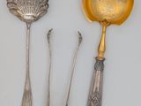 three silver spoons and a spoon rest on a white surface