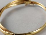 a close up of a gold bracelet on a white surface