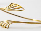 a close up of a gold cuff with a curved design on it