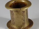 an old brass cup with a handle on a white surface