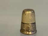 a gold thimble sitting on a white surface
