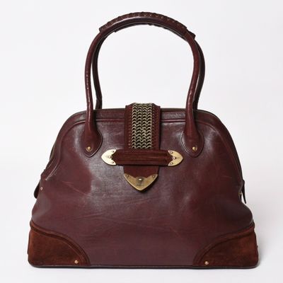 brown leather handbag with brass hardware on top of it