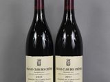 two bottles of red wine sitting on top of a glass table