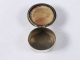 an old silver cup with a wooden lid sitting on a white surface