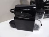a black coffee maker sitting on a counter next to a box of nesf nesf nesf nesf nesf nesf nesf nesf nes