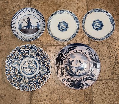 quatre assiettes bleues et blanches ornées de motifs, posées sur un sol carrelé