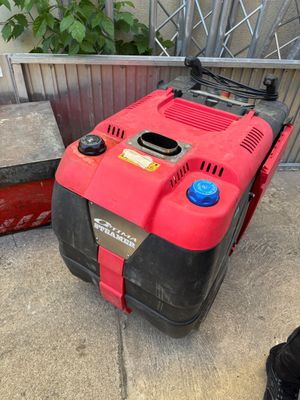 a red and black lawn mower sitting on the sidewalk