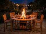 a fire pit sitting on a patio table with chairs around it
