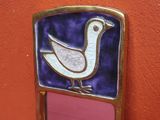 un petit miroir orné d'un oiseau, accroché au mur