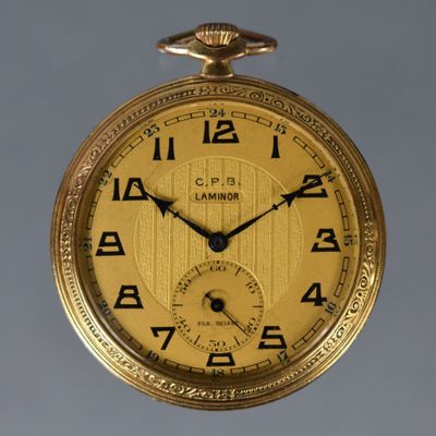 a gold pocket watch with roman numerals on the face