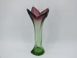 un vase en verre violet et vert posé sur une surface blanche