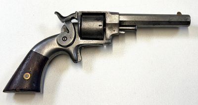 un vieux revolver avec une poignée en bois sur une surface blanche