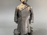 statue d'un homme en manteau et chapeau, debout sur un socle
