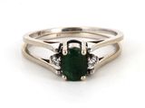 gros plan d'une bague avec une pierre verte et des diamants