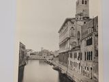 black and white photograph of a canal with a clock tower in the background