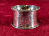 a silver plate with a monogram on it sitting on a red cloth