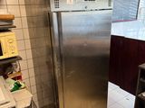 stainless steel refrigerator in a kitchen next to a stove and shelves