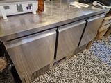 stainless steel counter top in a commercial kitchen with a microwave and refrigerator