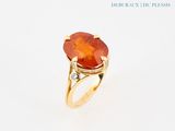 an image of a ring with an orange stone surrounded by diamonds