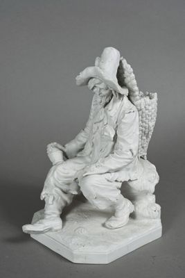 statue of a man sitting on a bench with a basket of grapes