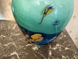 un vase bleu muni d'une étiquette, posé sur une table